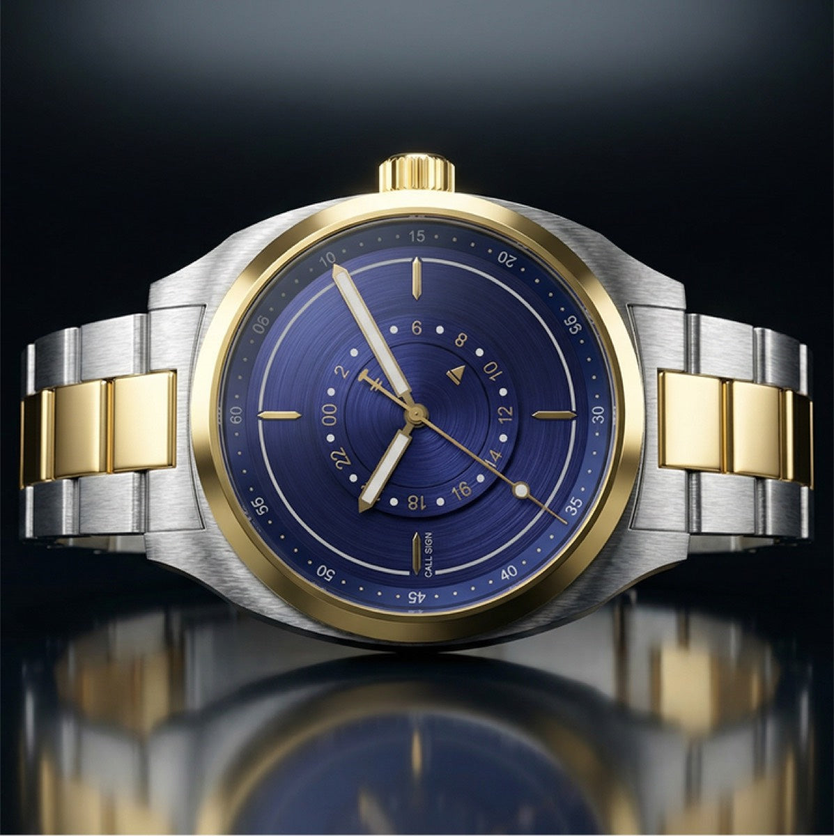 Cadre two-tone: blue dial with the central crescent GMT wheel, steel and gold-tone case and bracelet, on a dark ground.