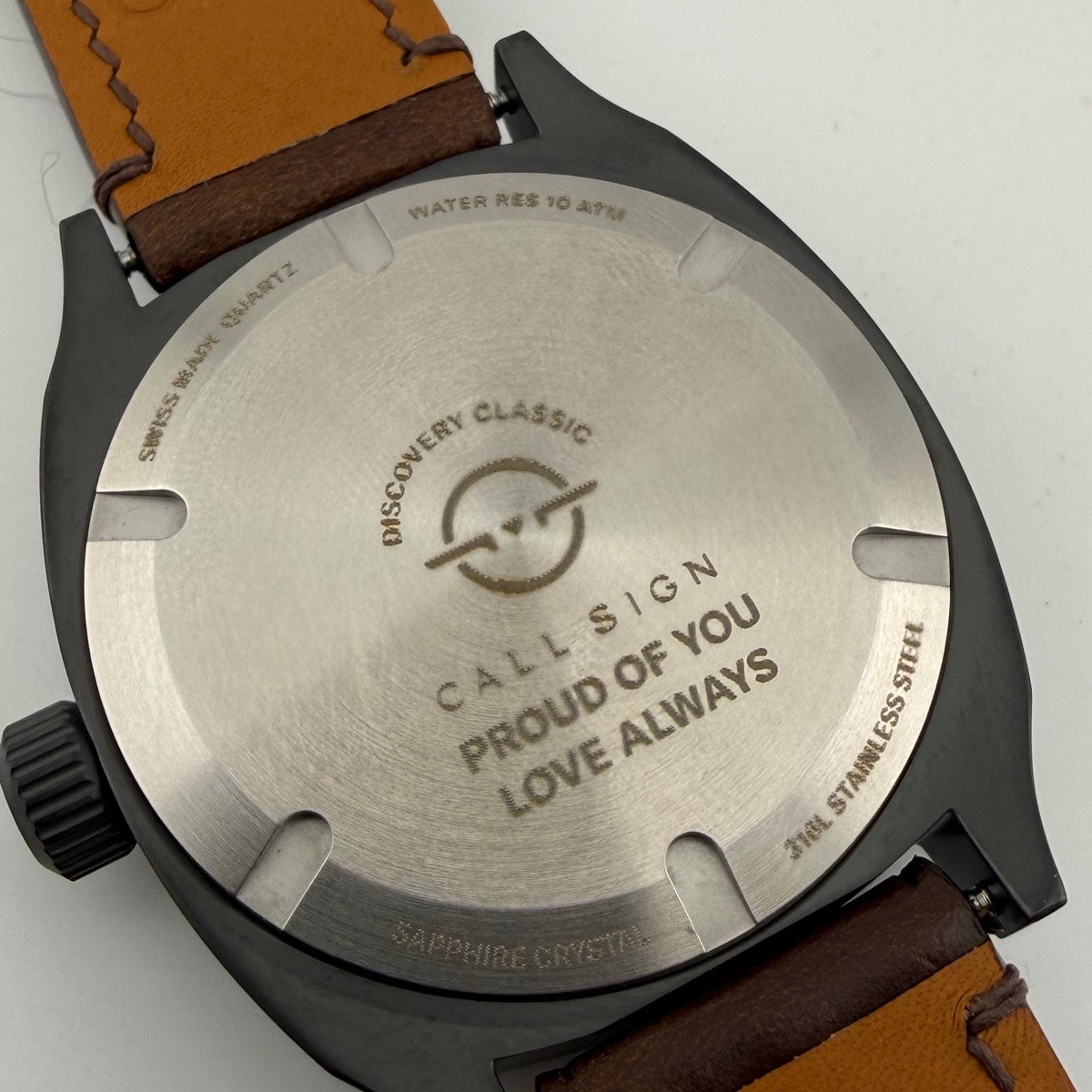 The steel caseback of a Discovery 38 engraved with two lines: PROUD OF YOU, LOVE ALWAYS.