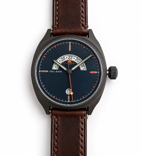 Discovery 38 Classic from the front: dark blue dial, orange accents, crescent GMT window at 12, brown leather strap.