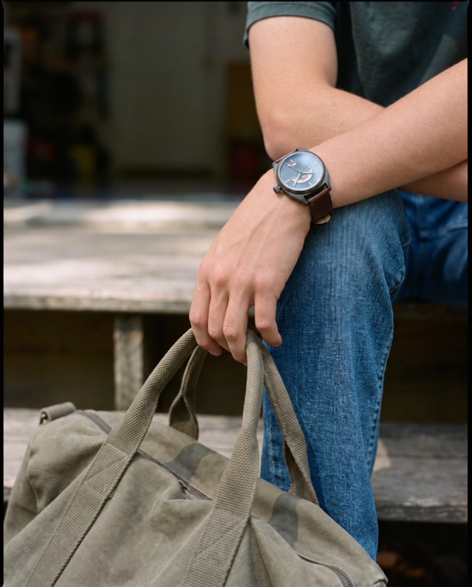 Sitting on the porch step with his bag beside him, watching the road, waiting for a ride.