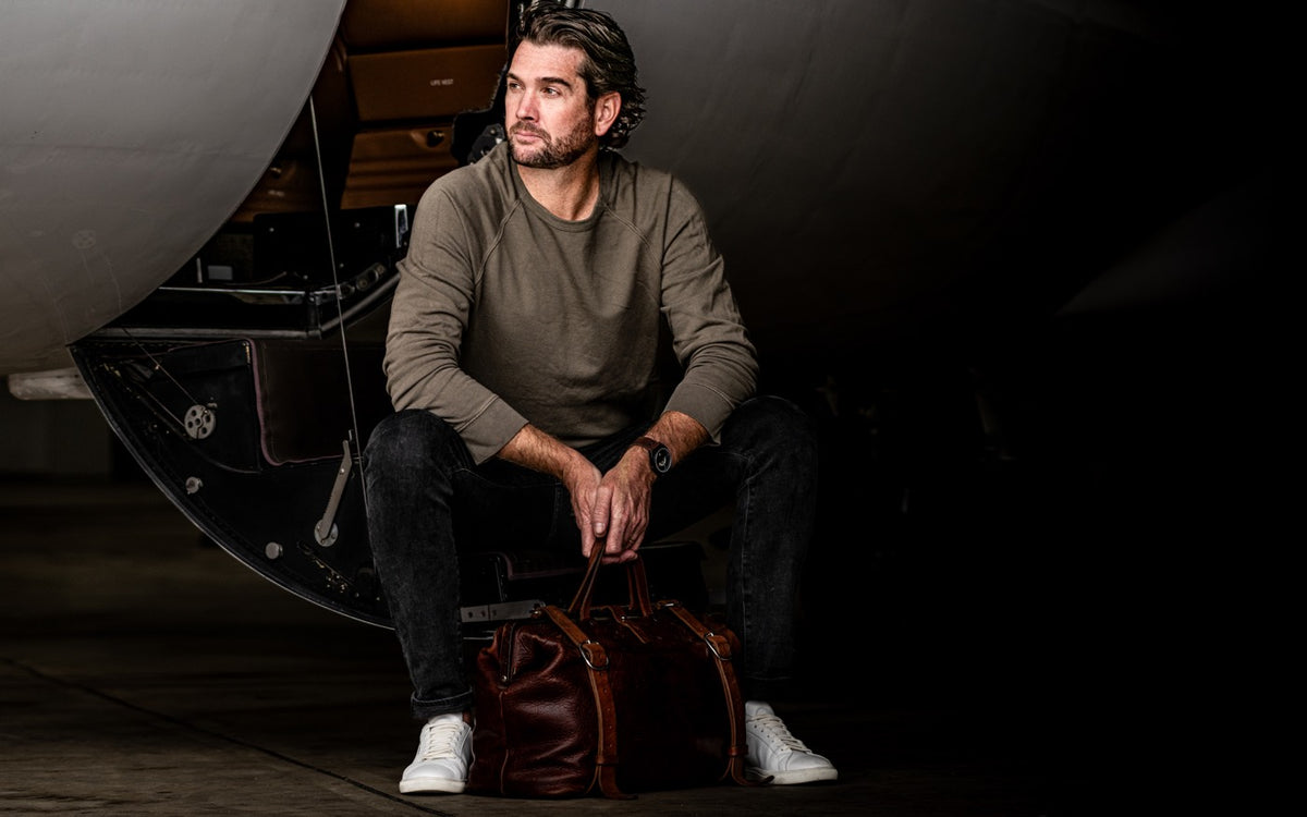 Seated on the airstair of a jet in a sweater and jeans, a leather bag at his feet, the Discovery on his wrist.